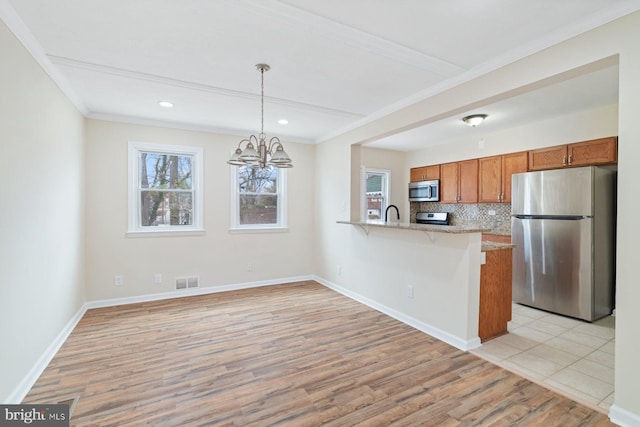 kitchen with pendant lighting, tasteful backsplash, kitchen peninsula, stainless steel appliances, and light hardwood / wood-style flooring