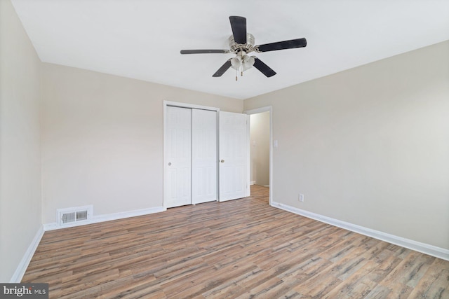 unfurnished bedroom featuring ceiling fan, wood-type flooring, and a closet