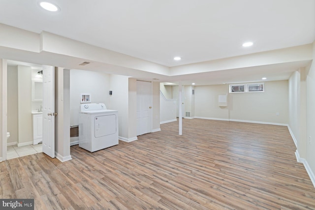 basement featuring washer / clothes dryer and light hardwood / wood-style flooring