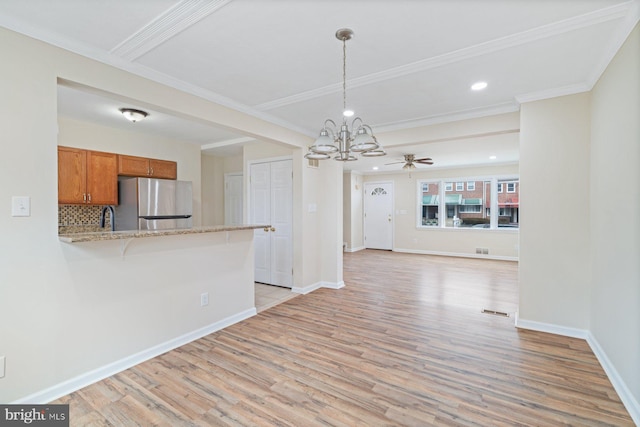 kitchen with pendant lighting, stainless steel refrigerator, tasteful backsplash, kitchen peninsula, and light wood-type flooring