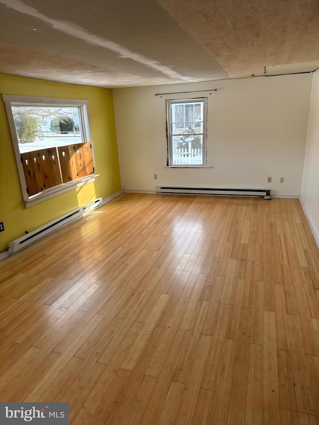 empty room featuring a baseboard heating unit and light hardwood / wood-style floors