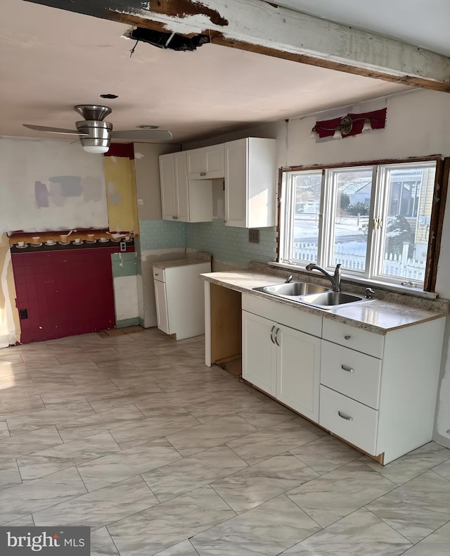 kitchen featuring white cabinetry, sink, tasteful backsplash, and ceiling fan