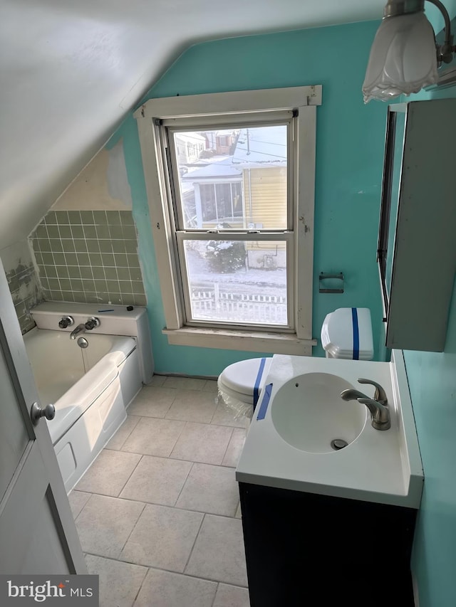 bathroom featuring tile patterned floors, a tub to relax in, toilet, lofted ceiling, and vanity