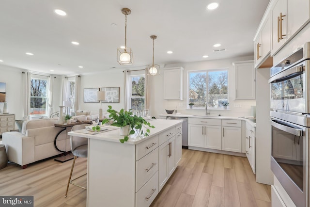 kitchen featuring appliances with stainless steel finishes, a center island, hanging light fixtures, and white cabinets