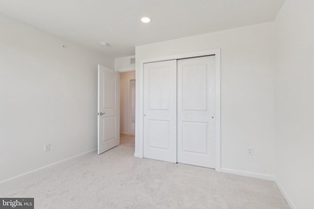 unfurnished bedroom featuring light colored carpet and a closet