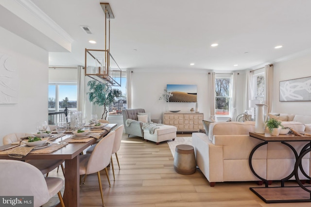 living room featuring a notable chandelier, ornamental molding, light hardwood / wood-style flooring, and a wealth of natural light