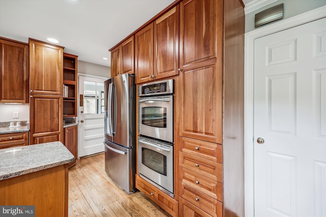 kitchen featuring open shelves, light stone counters, light wood finished floors, brown cabinetry, and stainless steel appliances