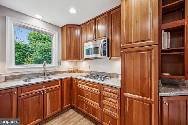 kitchen featuring light stone counters, a sink, brown cabinets, and stainless steel appliances