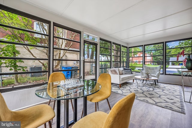 sunroom / solarium with an outdoor living space, outdoor dining space, and wood finished floors