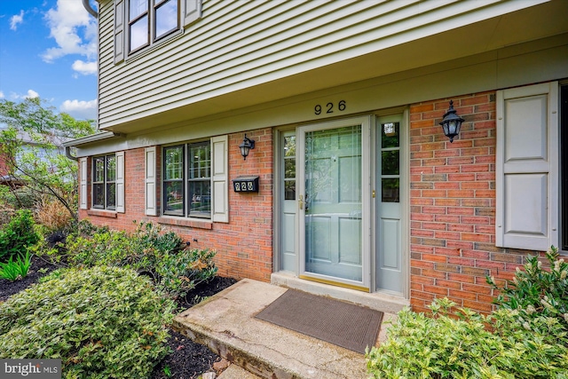 view of exterior entry featuring brick siding