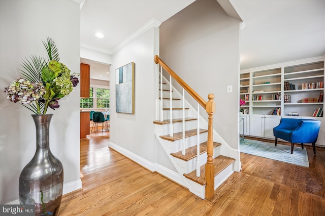 stairway with baseboards, ornamental molding, recessed lighting, and wood finished floors