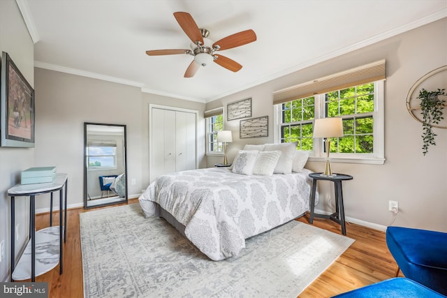 bedroom with crown molding, baseboards, a closet, and wood finished floors