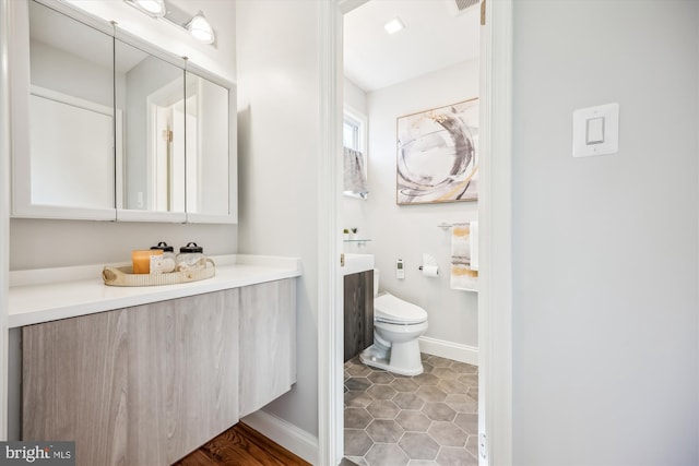bathroom with toilet, baseboards, tile patterned floors, and vanity