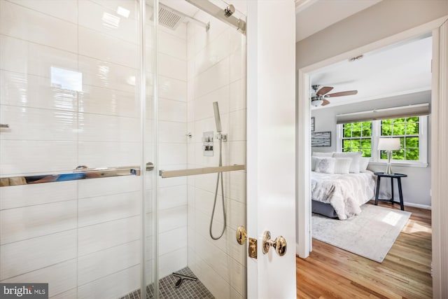 ensuite bathroom with a ceiling fan, a stall shower, ensuite bath, and wood finished floors
