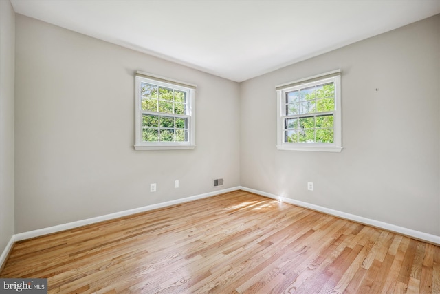 empty room featuring baseboards, wood finished floors, and visible vents