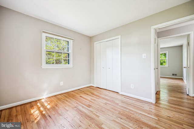 unfurnished bedroom with baseboards, visible vents, light wood finished floors, and a closet