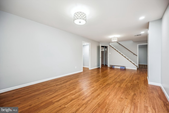 finished below grade area with baseboards, recessed lighting, light wood finished floors, and stairs