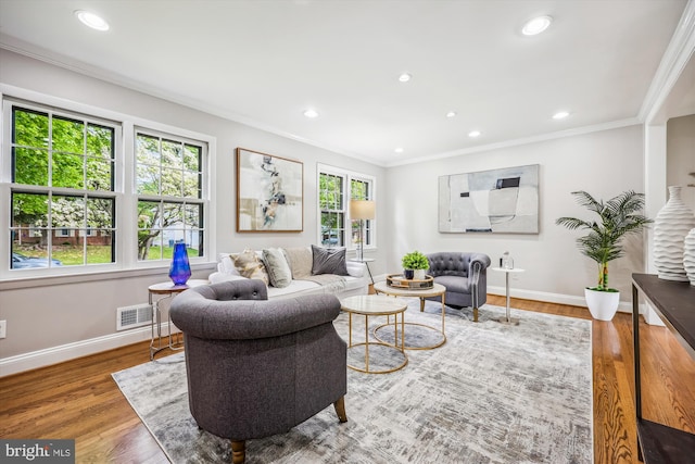 living area featuring crown molding, baseboards, wood finished floors, and visible vents