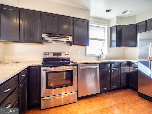 kitchen featuring light stone counters, appliances with stainless steel finishes, and light wood-type flooring