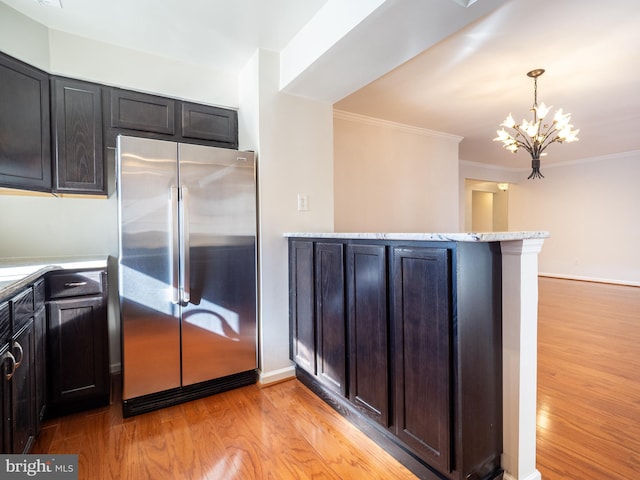 kitchen featuring stainless steel refrigerator, decorative light fixtures, ornamental molding, kitchen peninsula, and light wood-type flooring