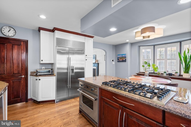 kitchen featuring white cabinetry, light stone counters, light wood-type flooring, and appliances with stainless steel finishes