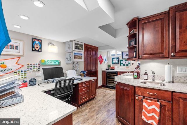 kitchen with beverage cooler, light stone countertops, sink, and light hardwood / wood-style flooring