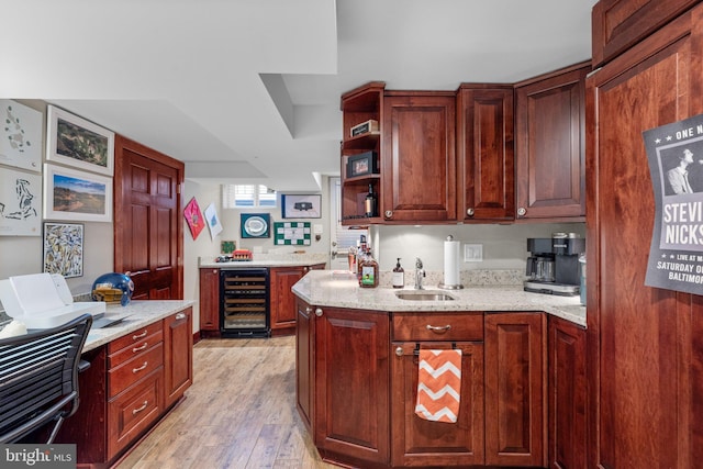 kitchen featuring light stone countertops, sink, beverage cooler, and light wood-type flooring