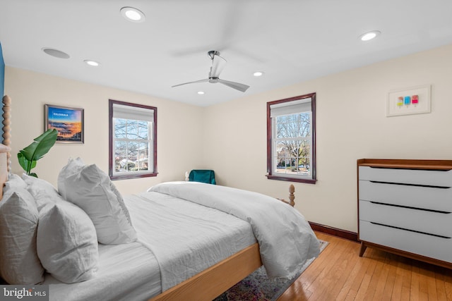 bedroom with multiple windows, light hardwood / wood-style floors, and ceiling fan