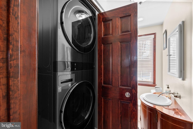 laundry area with stacked washer / drying machine and sink