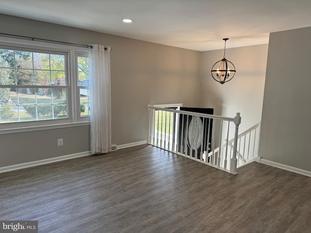 spare room featuring dark hardwood / wood-style flooring and a chandelier