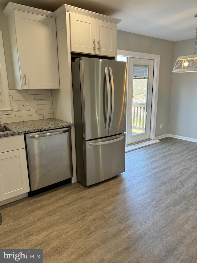 kitchen with white cabinetry, stainless steel appliances, light hardwood / wood-style flooring, and stone counters