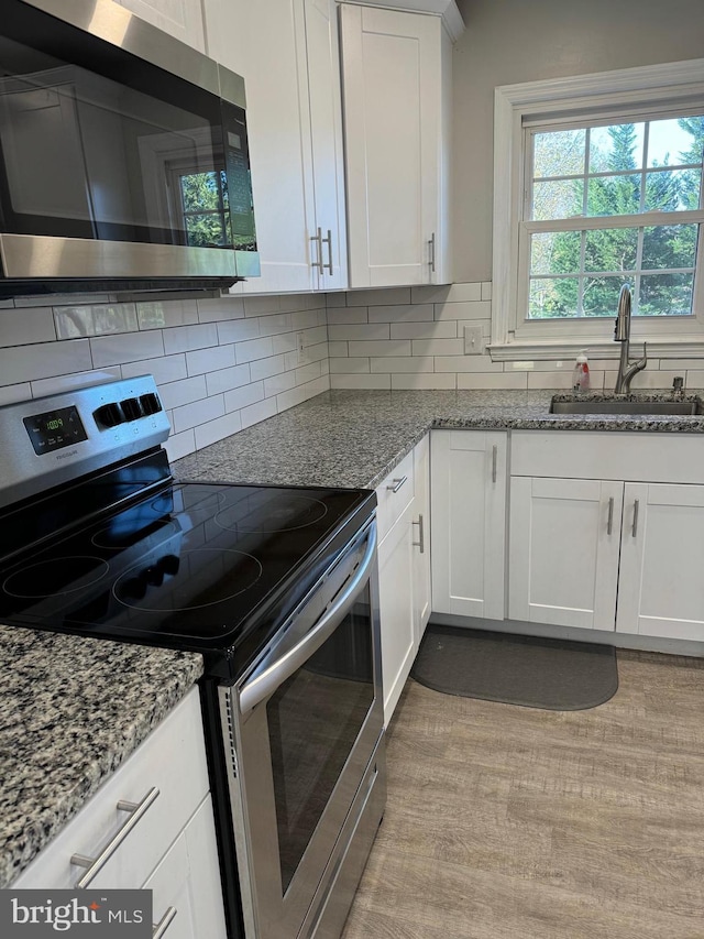 kitchen featuring white cabinetry, sink, stainless steel appliances, and light stone countertops