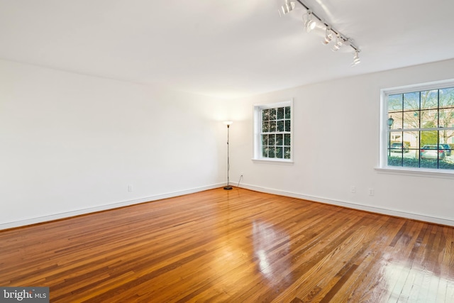 unfurnished room with track lighting and wood-type flooring