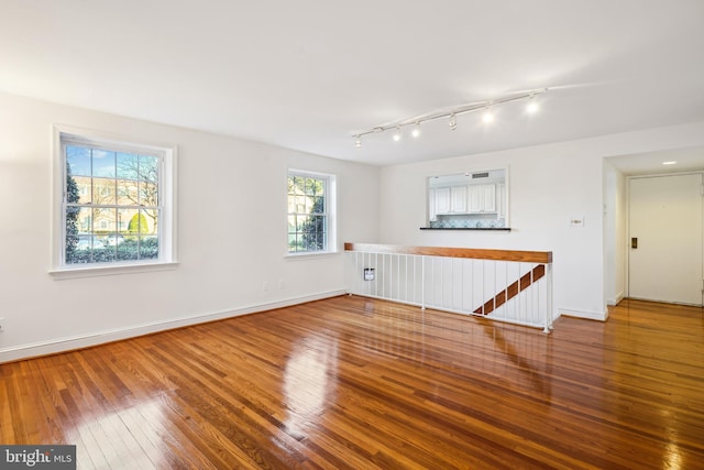 empty room with wood-type flooring and rail lighting