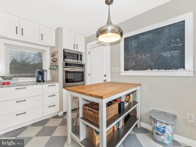 kitchen featuring stainless steel appliances, white cabinetry, hanging light fixtures, and butcher block counters