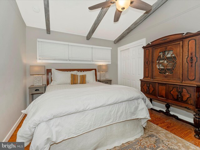 bedroom with wood-type flooring, lofted ceiling with beams, a closet, and ceiling fan