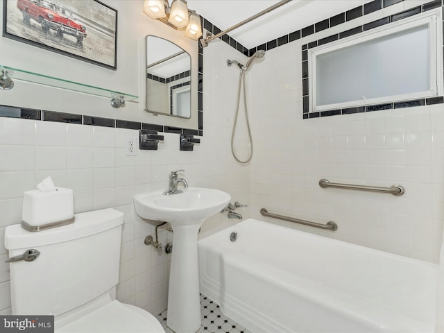 bathroom featuring tiled shower / bath, toilet, and tile walls