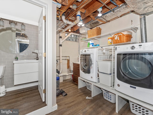 clothes washing area featuring washer and clothes dryer, sink, and dark wood-type flooring