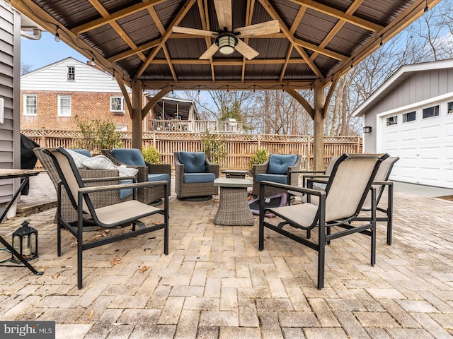 view of patio featuring a gazebo, ceiling fan, a garage, and an outdoor hangout area