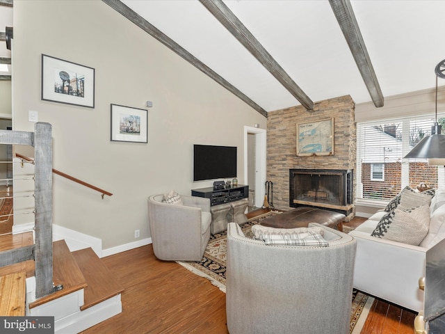 living room with dark hardwood / wood-style flooring, vaulted ceiling with beams, and a fireplace