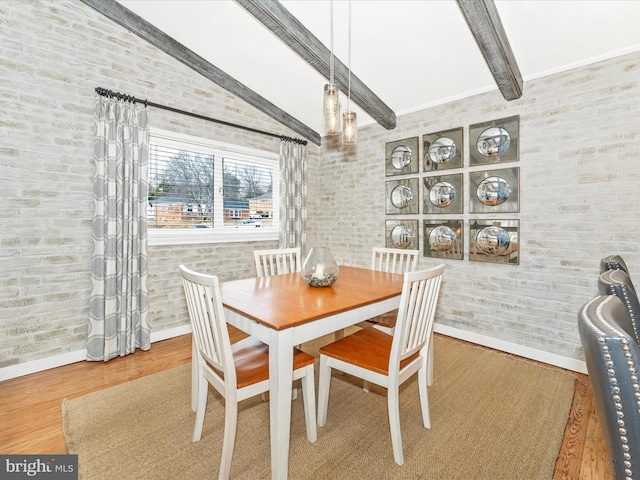 dining area with brick wall, wood-type flooring, and beam ceiling