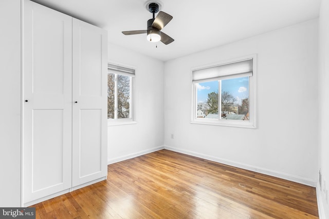 unfurnished bedroom featuring multiple windows, ceiling fan, and light wood-type flooring