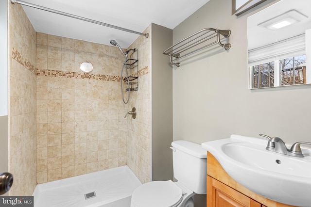 bathroom featuring vanity, tiled shower, and toilet