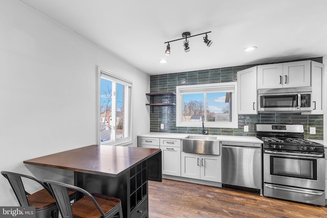 kitchen with backsplash, stainless steel appliances, sink, and white cabinets