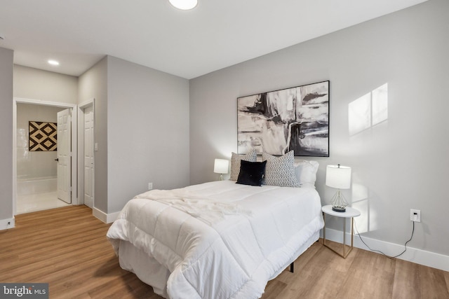 bedroom featuring ensuite bath and hardwood / wood-style floors