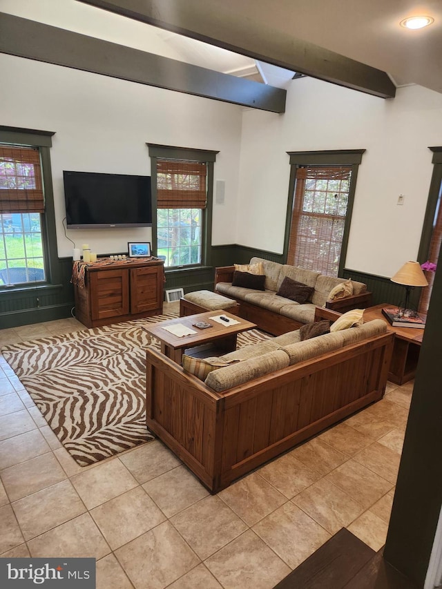 living room featuring a healthy amount of sunlight, vaulted ceiling with beams, and wainscoting