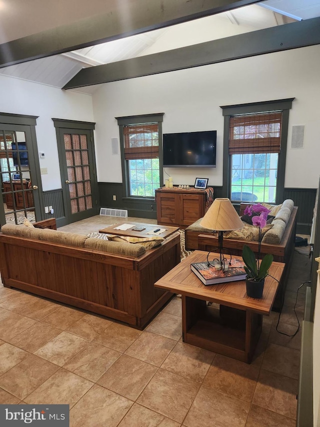 living area with visible vents, lofted ceiling with beams, a healthy amount of sunlight, and a wainscoted wall