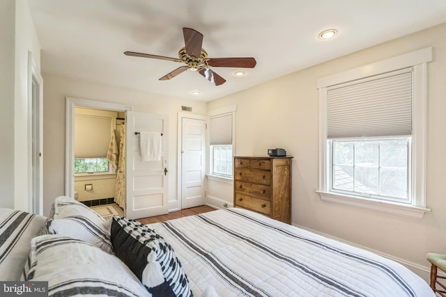 bedroom featuring visible vents, baseboards, wood finished floors, and multiple windows
