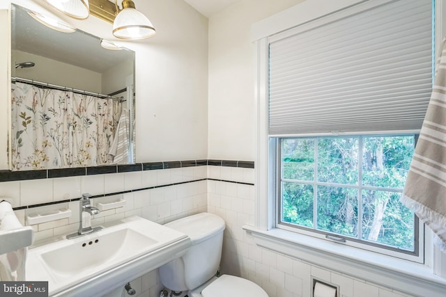 full bath featuring toilet, tile walls, and a sink