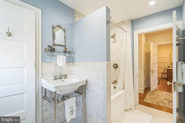 bathroom with shower / bath combo with shower curtain, tile walls, a sink, and recessed lighting